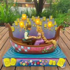 Déjate llevar por la magia de Enredados con este encantador diseño de Jim Shore, que captura a Rapunzel y Flynn Rider en un romántico paseo en bote iluminado por faroles LED flotantes.