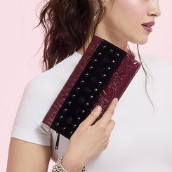 Oscura elegancia con actitud Disney. El Bolso bandolera Villanas Disney Loungefly combina un burdeos metalizado con relieves inspirados en las antagonistas más icónicas y una banda frontal de efecto terciopelo