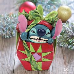 Stitch, el travieso alienígena, trae diversión y alegría navideña en esta encantadora creación de Jim Shore. En medio de un festivo papel de regalo, Stitch irrumpe desde un colorido presente