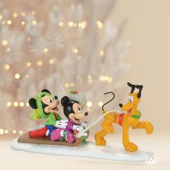 La figura de porcelana "Pluto's Toboggan Ride" representa una divertida escena invernal con Pluto, Mickey y Minnie Mouse disfrutando de un paseo en trineo. Pluto, el fiel perro de Mickey